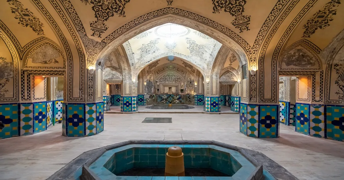 Ornate bathhouse interior with tiled columns and a central basin